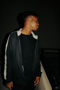 a man in a black jacket standing on a railing