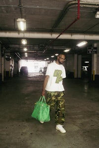 a man carrying a green bag in a parking garage